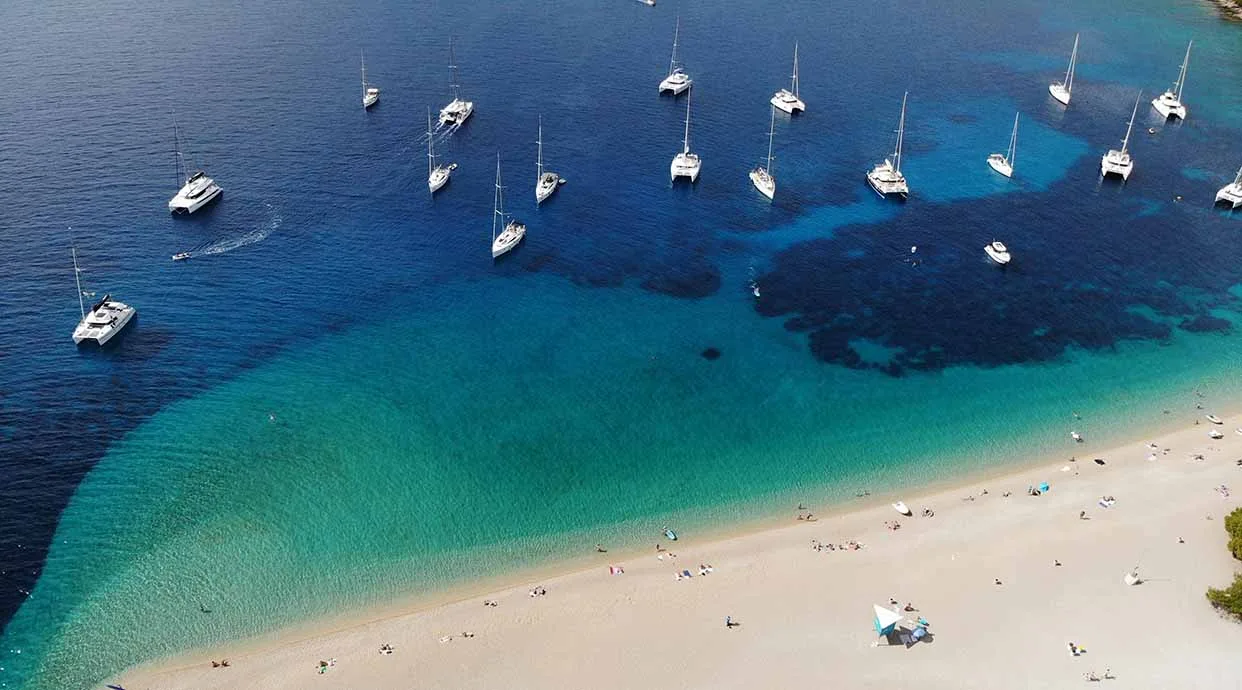 veleros y catamaranes fondeando en la famosa playa croata de Zlatni Rat